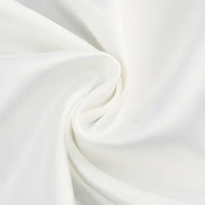 Macro view showing the smooth texture and elegant sheen of the white evening gown fabric.