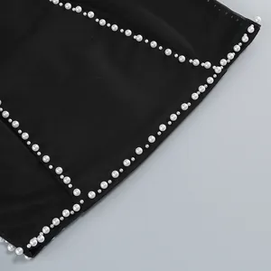 Primer plano de elegantes perlas blancas cosidas en un vestido de vendaje de malla