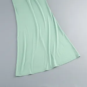 Primer plano del dobladillo de un vestido verde menta con textura de tela lisa y costura.