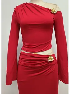 Detalle del conjunto rojo de dos piezas con hombro caído y broches de flores doradas.