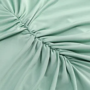 Detalle de primer plano de vestido verde menta con tejido fruncido y costuras plisadas