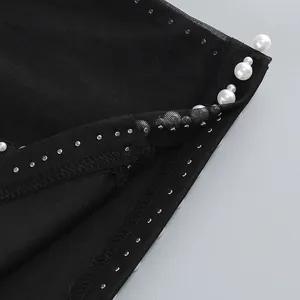 Primer plano de los detalles de perlas y malla en un vestido bandage negro de alta costura
