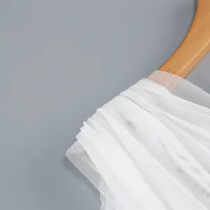 Detalle exquisito de tela de malla blanca suave y transpirable en una percha de madera