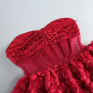 Detalle de vestido rojo sin tirantes con cuentas y diseño de flores 3D