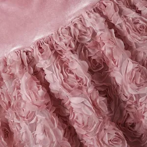 Primo piano del complesso pizzo rosa 3D e del tessuto in velluto di un abito da sera.
