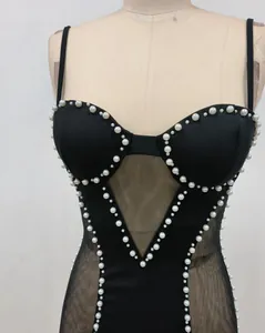 Detalle de un vestido bandage negro con adornos de perlas y paneles de malla transparente