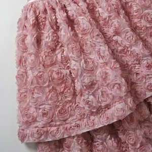 Primo piano di rose in tessuto 3D rosa su un dettaglio di tessuto per abito francese