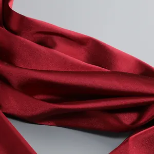 Detalle de la textura de tela satinada rojo vino con pliegues elegantes y brillo