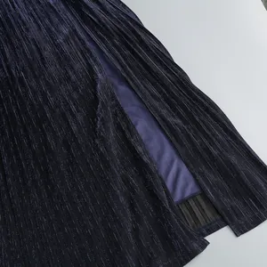 Detailed view of deep blue pleated fabric with a high side slit on an evening gown.