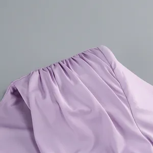 Primer plano del elegante detalle fruncido en el hombro de un vestido de fiesta morado