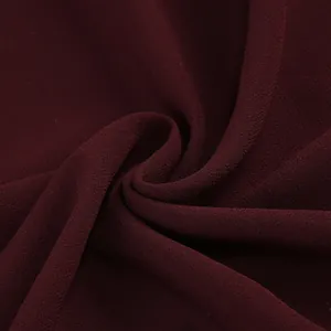 Primer plano detallado que muestra la elegante textura de la tela de un vestido de gala burdeos