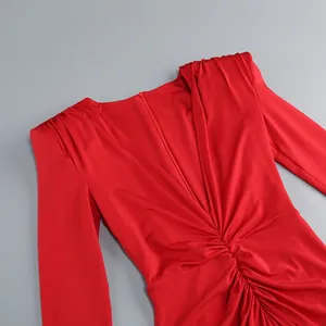 Detalle de vestido rojo de manga larga con cuello en V, fruncido y pliegues en los hombros