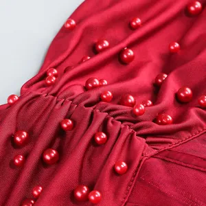 Vista macro de detalles de perlas rojas en tela de satén fruncida de un vestido corto