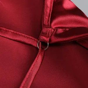 Vista detallada de las costuras finas y el anillo de metal en un vestido de satén rojo.