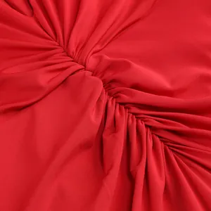 Primer plano detallado del fruncido en un vestido de noche rojo con cuello en V y manga larga