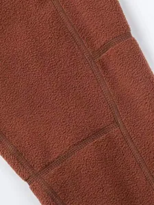 Detailopname van de textuur en naden van een dikke roestbruine fleece stof voor jassen.