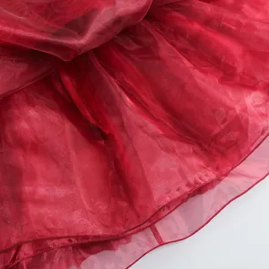 Vista detallada del tejido de malla roja en capas y las costuras del dobladillo de falda.