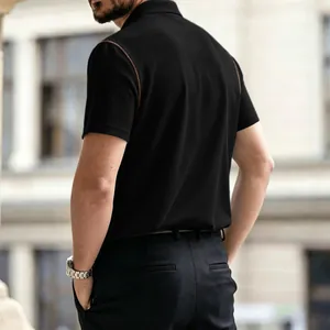Back view of black waffle knit men's polo shirt with brown shoulder stitching