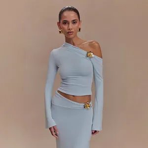 Conjunto azul claro de top de un hombro y falda larga con detalles de flores doradas
