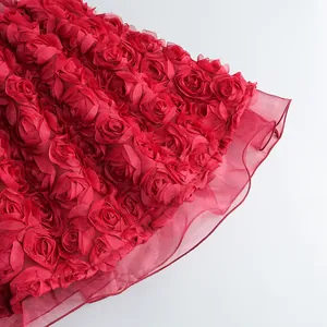Detalle de cerca de la tela con rosas 3D y el dobladillo de tul de un vestido de fiesta rojo