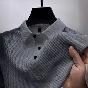 Macro detail of men's grey textured ice silk polo shirt showing fabric quality and buttons