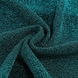 Gros plan sur un tissu lurex sarcelle scintillant avec texture froissée en soie dorée.