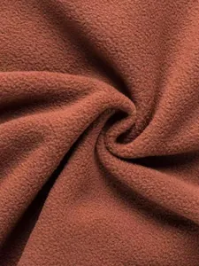 Macrodetail van bruine polarfleece stof met zachte en warme textuur voor jassen.