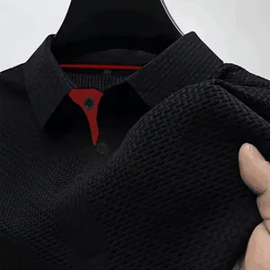 Detail shot of black waffle texture polo shirt with red collar accent and XXL size label.