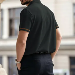 Detalle de polo de punto gofrado negro para hombre con ribete dorado en la manga