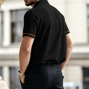 Vista detallada de un polo de punto negro de manga corta con rayas doradas en mangas.