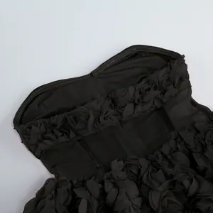 Primer plano de un vestido de fiesta negro sin tirantes con texturas de pétalos de flores 3D.