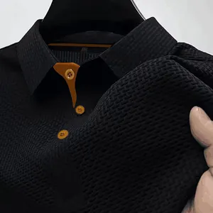 Detalle del polo negro con textura de punto elástica transpirable y detalles naranjas