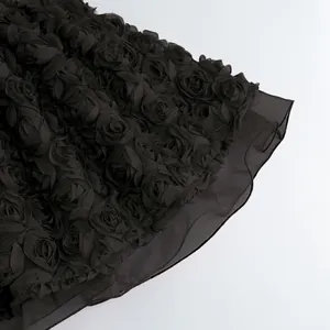 Primer plano de rosas de tela 3D negras y capas de malla transparente en el dobladillo