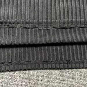 Close-up of double-stitched hem and ribbed texture on men's black sports vest.