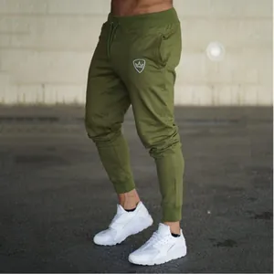 Detail shot of men's olive green slim-fit drawstring joggers featuring a small crown logo accent
