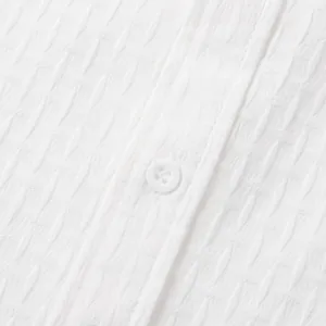 Macro detail showing the textured white jacquard fabric and button on a men's summer shirt