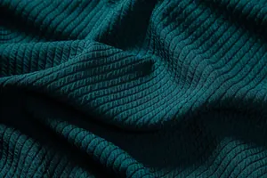 Close-up detail of high-quality textured dark teal fabric with intricate ribbed weave
