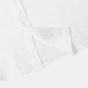Close-up of white men's short sleeve shirt showing detailed jacquard texture.