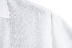 Macro detail of white summer shirt showing breathable crinkle fabric texture and seam.