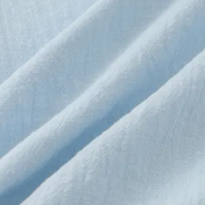 Detailed macro shot showing the breathable texture of light blue linen shirt fabric