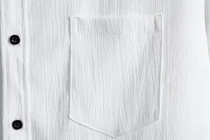 Macro view of chest pocket and black buttons on white textured casual men's summer shirt