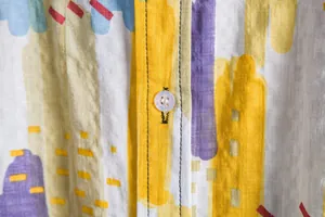 Close-up of vibrant floral pattern and transparent button on men's summer short sleeve shirt