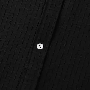Macro view showing the intricate black jacquard fabric texture and white button of this shirt