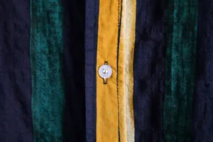 Macro detail of the textured cotton fabric and white button on a striped Hawaiian shirt