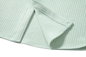 Close-up view of the light green ribbed fabric hem and stitching detail for a casual shirt.