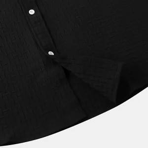 Detailed view of the black jacquard textured fabric and white buttons on a men's shirt