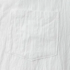 Close-up detail of a white linen cotton shirt pocket showing natural texture and stitching.