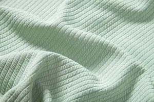 Macro view of light green ribbed fabric texture for men's casual shirt details.