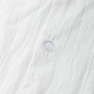 Close-up view of white breathable cotton linen fabric texture and button detail