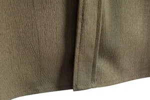 Close-up of olive brown textured fabric and stitching on a men's casual shirt